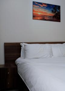 uma cama com lençóis brancos e uma foto na parede em Luxe Living Mbuya em Kampala