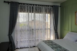 um quarto com uma cama e uma janela com cortinas em Luxe Living Mbuya em Kampala