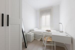 a white bedroom with a table and a bed at Stay Barcelona Long Term Camp Nou in Barcelona