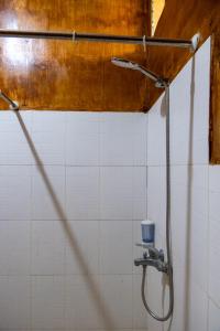 La salle de bains est pourvue d'une douche et d'un mur carrelé blanc. dans l'établissement Rinjani Eco Villa, à Bayan