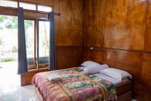 - une chambre avec un lit et un mur en bois dans l'établissement Rinjani Eco Villa, à Bayan