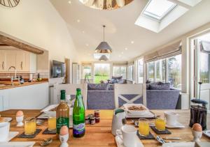 cocina y sala de estar con mesa de madera y botellas en White House Lodges - Dragonfly en Heveningham