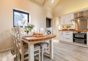 a kitchen with a wooden table with chairs and a dining room at White House Lodges - Nightingale in Heveningham
