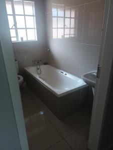 un bagno bianco con vasca e lavandino di Kya Sand Guesthouse a Johannesburg