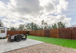 a patio with tables and chairs and a fence at Cherry Trees - Acton in Waldingfield