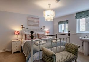 1 dormitorio con cama, silla y lavamanos en Orford Cottage en Aldeburgh