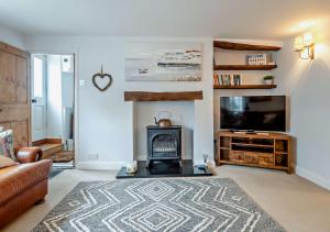 sala de estar con chimenea y TV de pantalla plana en Orford Cottage en Aldeburgh