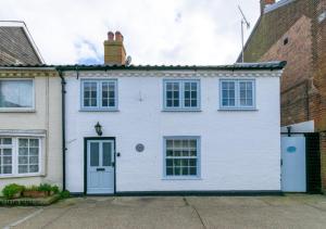 una casa blanca con una puerta azul en Orford Cottage en Aldeburgh