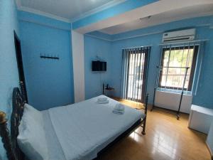 a bedroom with blue walls and a bed with white sheets at Magnolia in Kutaisi