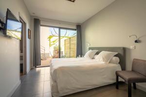 - une chambre avec un grand lit blanc et une chaise dans l'établissement Lafitenia Resort, à Saint-Jean-de-Luz