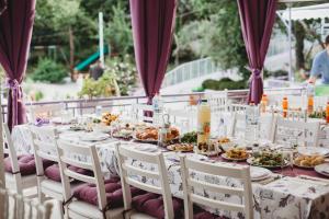 a long table with white chairs and plates of food at Парк-хотел РИВА in Golden Sands