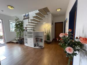 a living room with a staircase and flowers at Pension Haus My in Norddeich