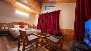 a bedroom with a bed and a table and a tv at Villa Pink Bud 6BHK in Manāli