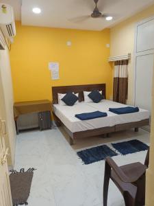 - une chambre avec un lit et un mur jaune dans l'établissement Chitrakut Bungalows, à Dwarka