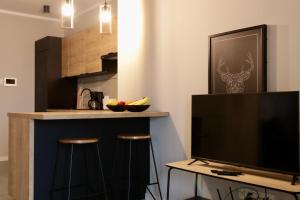 een keuken met een bar met krukken en een televisie bij Capital Towers Prime in Rzeszów