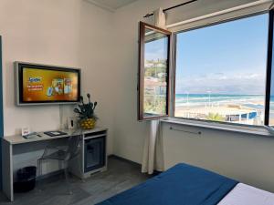 una camera con letto, scrivania e finestra di Hotel La Battigia ad Alcamo Marina