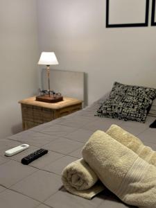 Una cama con una toalla y un mando a distancia. en Ocean Apartments en Ciudad Lujan de Cuyo