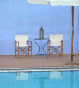 - deux chaises et une table à côté de la piscine dans l'établissement 4 Beds Flat with Shared Pool, à Stalida