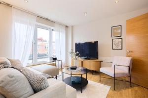 uma sala de estar com um sofá e uma televisão em The Battersea Park Place - Amazing 2BDR Flat with Terrace em Londres