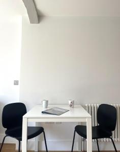 una mesa blanca con 2 sillas negras en una habitación en Harbourside Haven - One Bed Apartment with Balcony, en Bristol