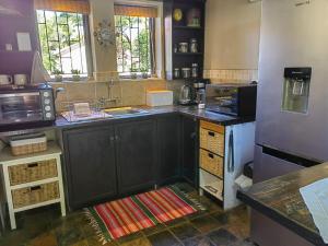 Teas & Seas Self Catering Cottage في كيب تاون: مطبخ مع مغسلة وثلاجة