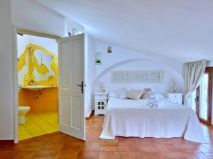 a white bedroom with a bed and a bathroom at Le Andira - Monolocali finemente arredati a pochi passi dal centro storico di Orosei in Orosei
