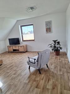 un salon avec une chaise et une télévision dans l'établissement Bergblick-FeWo, à Hohenstein-Ernstthal