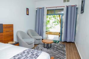 um quarto com uma cama, 2 cadeiras e uma janela em Ruhondo Beach Resort em Ruhengeri