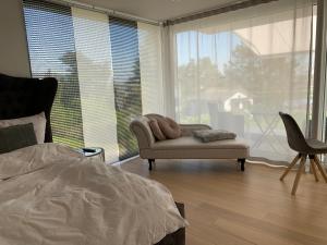 a bedroom with a bed and a chair and a window at Deluxe Doppelzimmer mit Pool und Aussicht in Dänikon