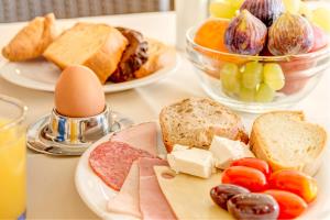 une table recouverte de assiettes de nourriture avec du pain et des fruits dans l'établissement Sunrise Beach Suites, à Azolimnos