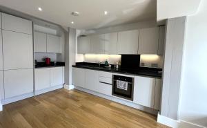 a kitchen with white cabinets and a wooden floor at Harbourside Haven - One Bed Apartment with Balcony in Bristol