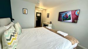 um quarto com uma cama branca e uma televisão na parede em Smart Hyde Park View Hostel em Londres