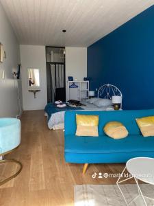 uma sala de estar azul com um sofá e uma cama em Chambre Californie - Old School em Port-Joinville