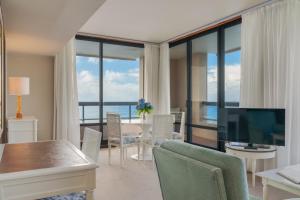 a living room with a television and a table with chairs at Pestana Bahia Praia Nature & Beach Resort in Vila Franca do Campo