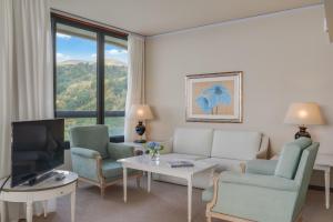 a living room with a couch and chairs and a tv at Pestana Bahia Praia Nature & Beach Resort in Vila Franca do Campo