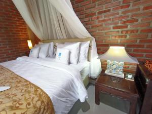 ein Schlafzimmer mit einem weißen Bett und einer Ziegelwand in der Unterkunft Coco Garden Pool Villas in Kubutambahan