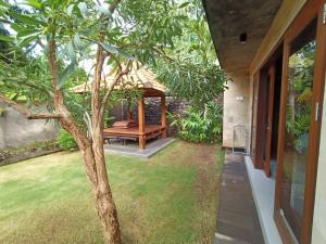 einen Garten mit einem Pavillon und einem Baum in der Unterkunft Coco Garden Pool Villas in Kubutambahan