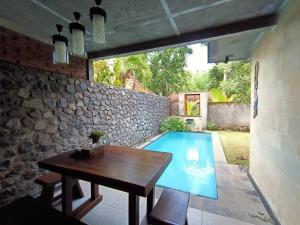 eine Terrasse mit einem Tisch und einem Pool in der Unterkunft Coco Garden Pool Villas in Kubutambahan