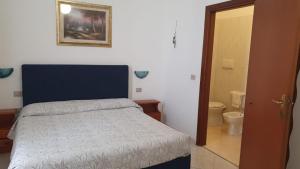 a bedroom with a bed and a bathroom with a toilet at Hotel 4 Mori in Cagliari