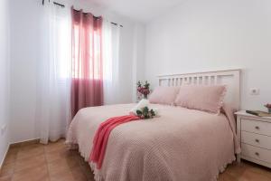 a white bedroom with a bed with a pink blanket at Laguna 3 Rooms Piscina in Chipiona