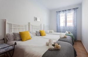 a bedroom with two beds with yellow and blue pillows at Laguna 3 Rooms Piscina in Chipiona