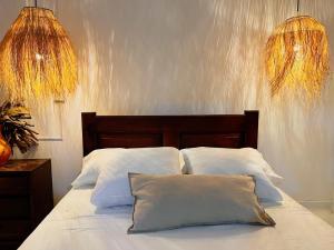 uma cama com lençóis brancos e duas almofadas em Hermosa habitación en casa campestre con piscina cerca al aeropuerto em Santa Marta