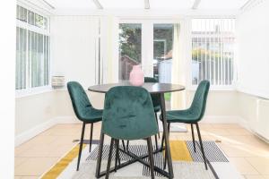 a dining room with a table and four green chairs at Stylish 3 Bed House Near Hospital, Racecourse, Free Parking 