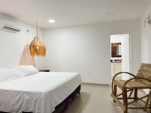 a bedroom with a bed and a chair and a chandelier at Hermosa habitación en casa campestre con piscina cerca al aeropuerto in Santa Marta