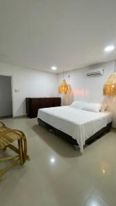 um quarto com uma cama grande e 2 lustres em Hermosa habitación en casa campestre con piscina cerca al aeropuerto em Santa Marta