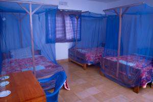 a room with three beds and a wooden table at STC.SAFARI LODGE in Oldeani