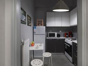 una pequeña cocina con electrodomésticos blancos y una mesa pequeña en The Acropolis Apartment, en Atenas
