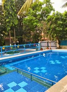 a large swimming pool with blue tiles and trees at Classic Villa 3 BHK Villa with pool in chondhi, Kihim, Alibag in Alibag