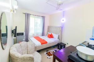 1 dormitorio con cama, silla y lavamanos en Greer Homes Sun Sweet, en Shanzu