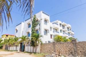 un edificio blanco con palmeras frente a una pared en Greer Homes Sun Sweet, en Shanzu